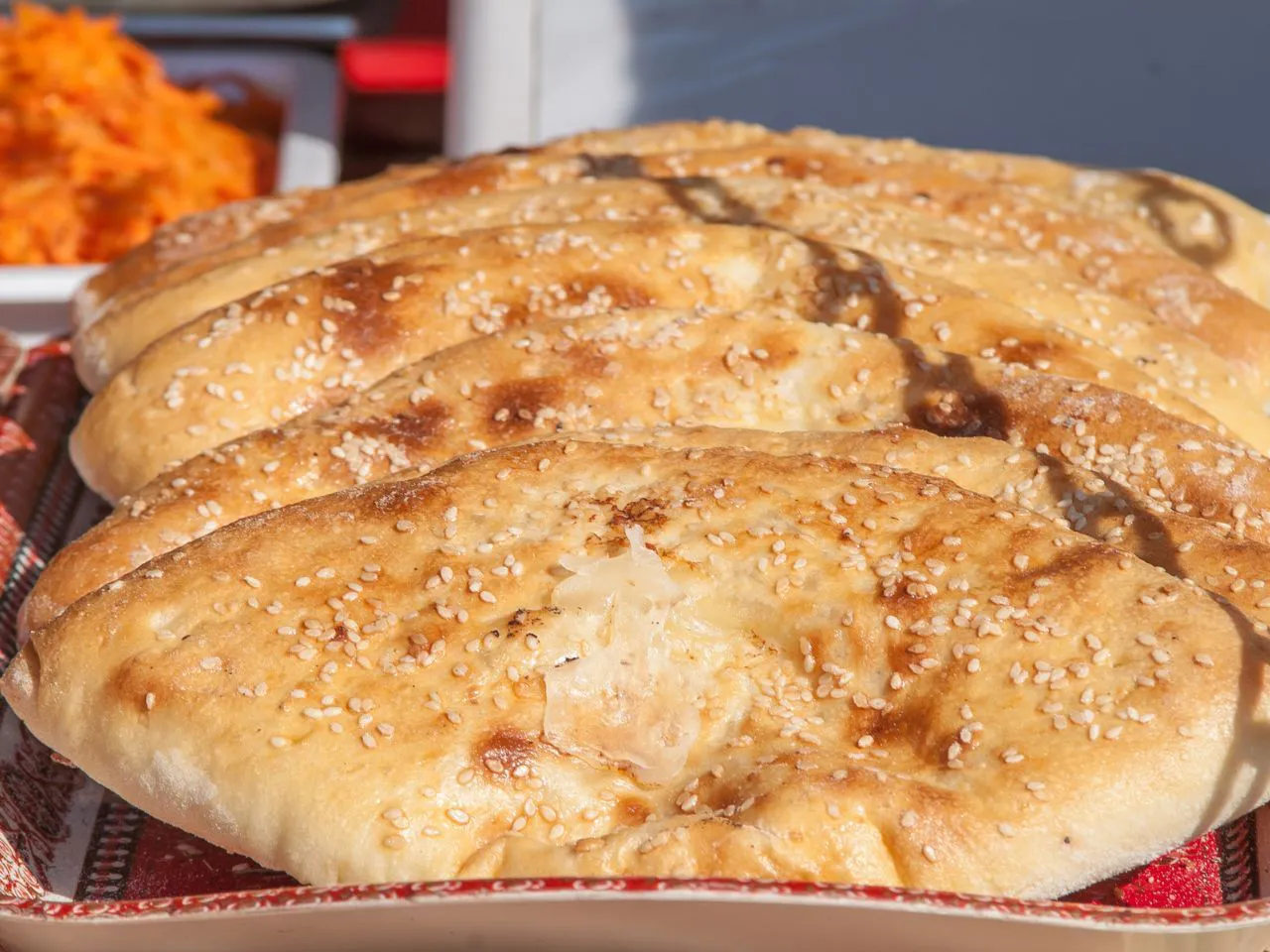 Rows of flat sesame baked bread lined up on a patterned tray at Authentic Yongtai Scallion Pie & Shi Wei BBQ, a Chinese Restaurant in Brooklyn