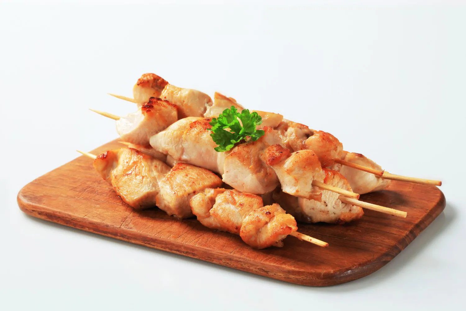 Simple grilled white chicken skewers arranged on wooden serving board at Authentic Yongtai Scallion Pie & Shi Wei BBQ, a Chinese Restaurant in Brooklyn